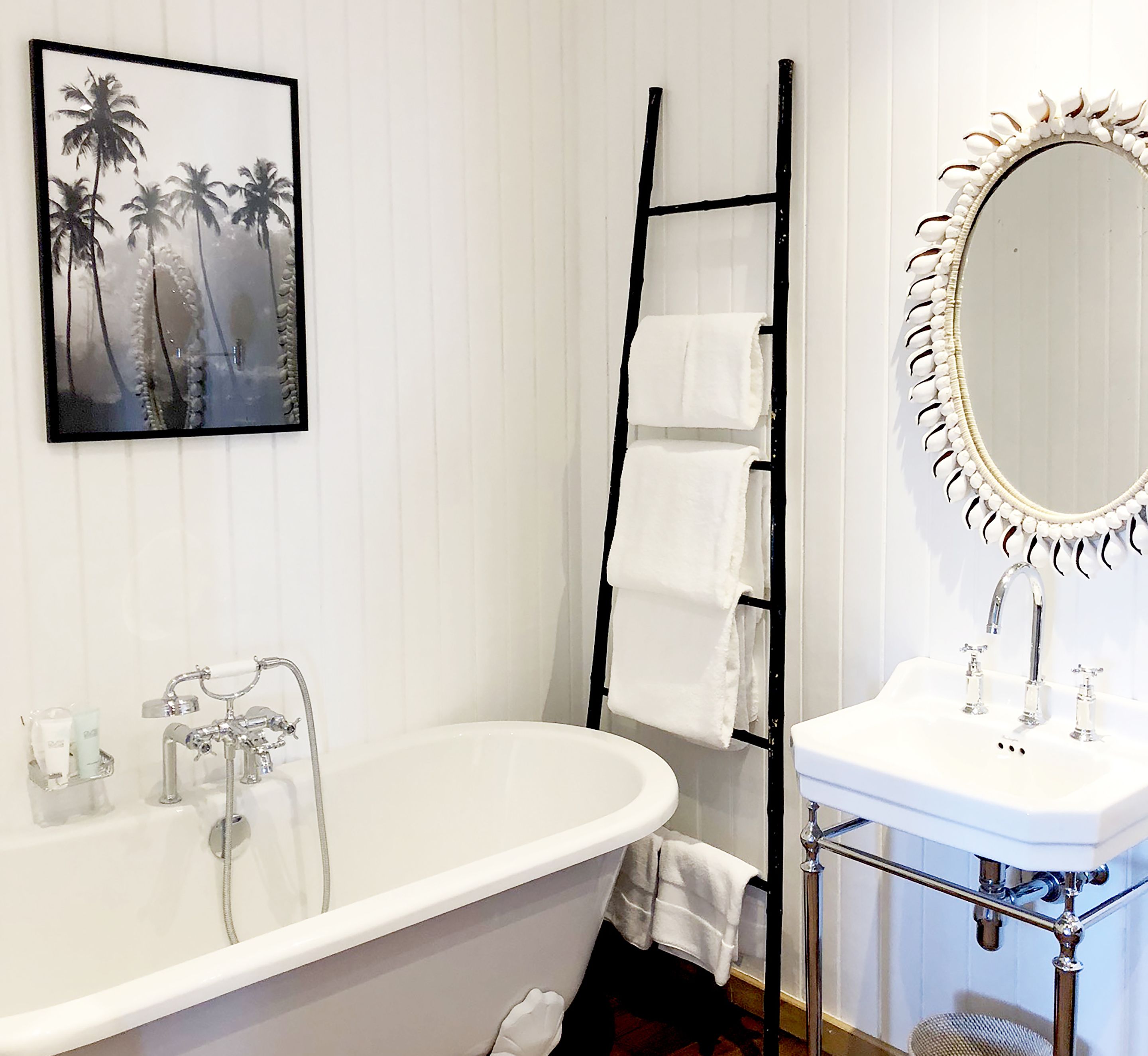 A bathroom with a freestanding bathtub, a white sink with a mirror, and a towel rack.