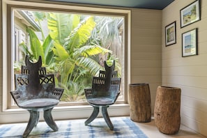 Two rustic chairs with a unique design, positioned near a large window with a view of lush greenery.