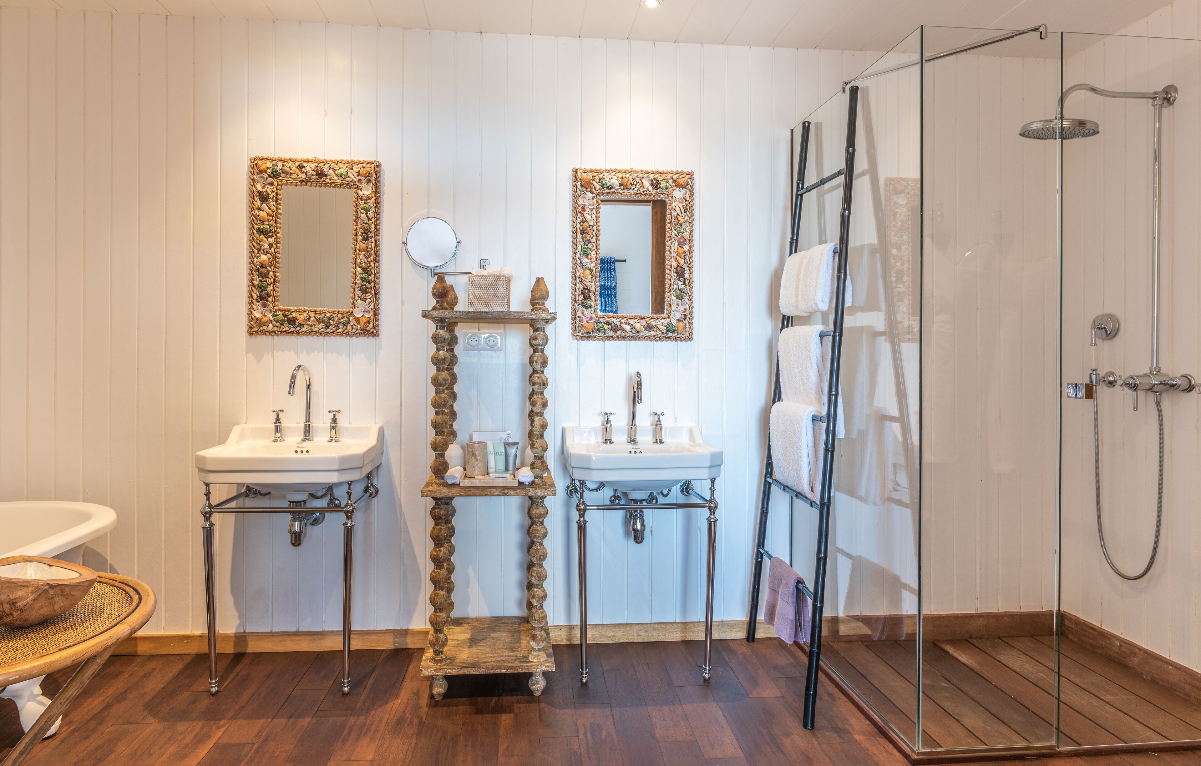 A bathroom with two sinks, a mirror, a shower, and a wooden shelf.