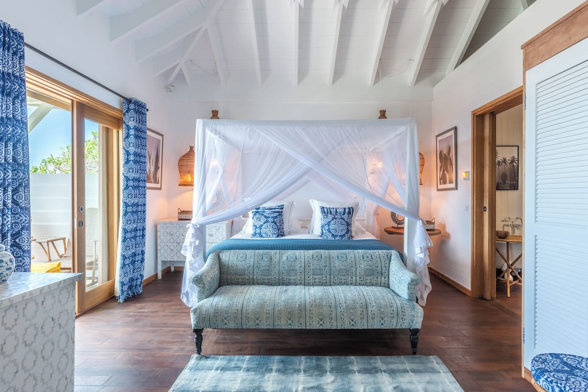 Un dormitorio con cama con dosel, dosel decorativo, ropa de cama estampada y vistas al exterior.