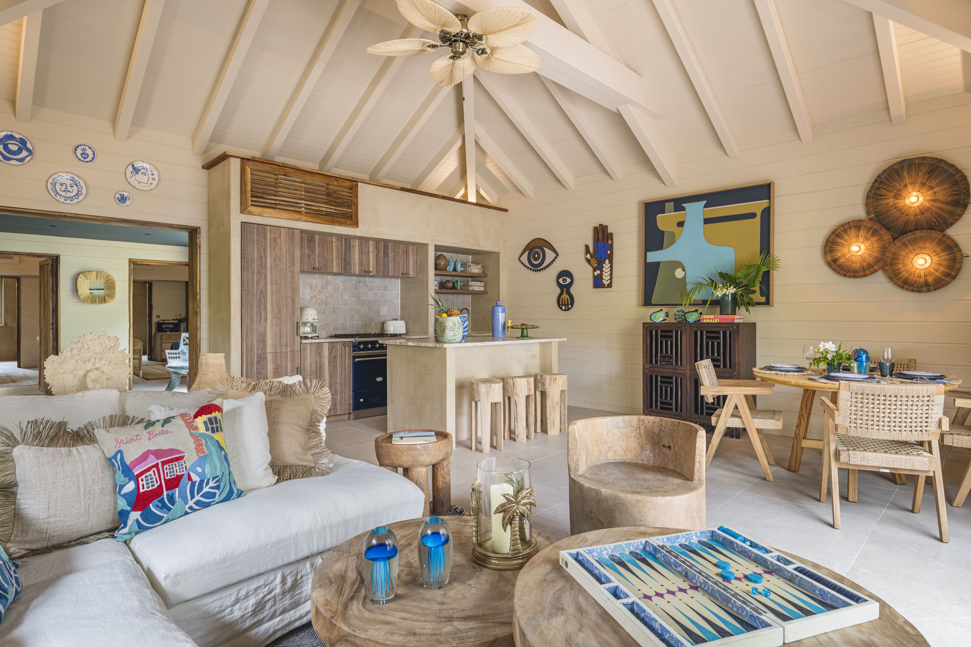 A spacious living area with a high ceiling, a dining area with wooden furniture, and a kitchen with modern appliances.