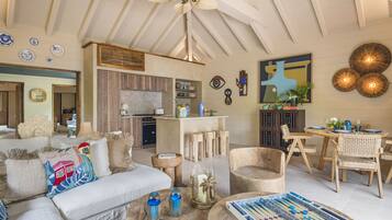 A spacious living area with a high ceiling, a dining area with wooden furniture, and a kitchen with modern appliances.
