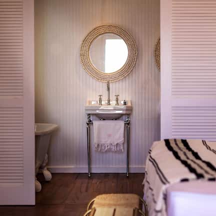 A bathroom with a round mirror, a sink, and a toilet.