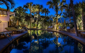 A pool area with lounge chairs and umbrellas, surrounded by palm trees and a wooden deck. - GYP SEA Saint Barth (St. Barthelemy)