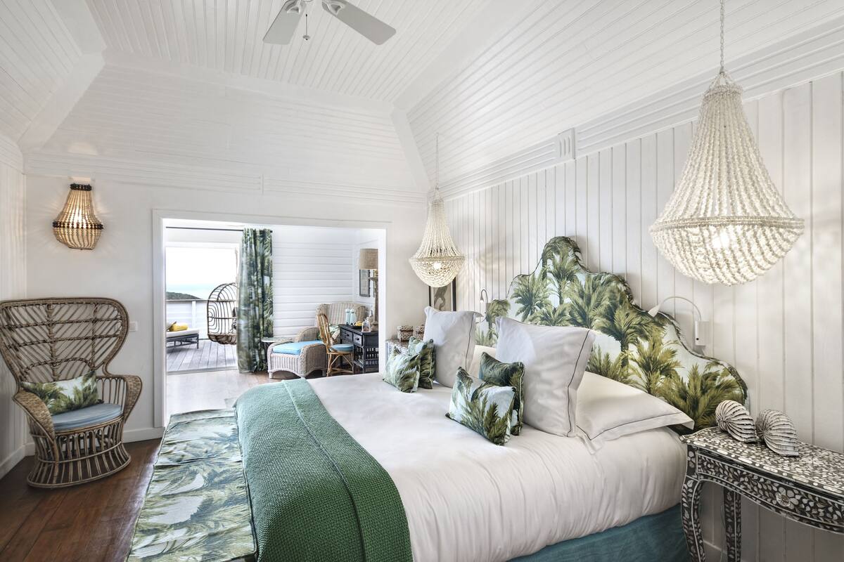 Un dormitorio amplio con una cama grande, una silla de mimbre y vistas al exterior.