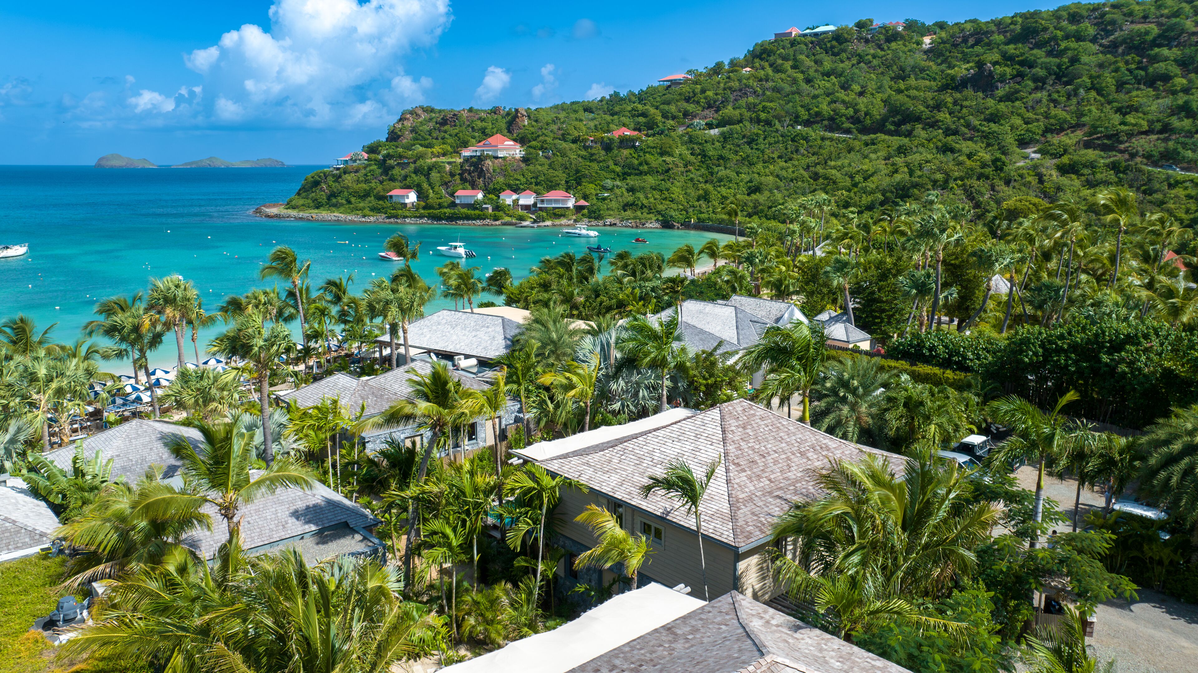 A coastal resort with multiple bungalow-style buildings, a beach, and boats in the water.