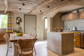 A spacious kitchen with a central island, wooden cabinets, and a tiled backsplash.