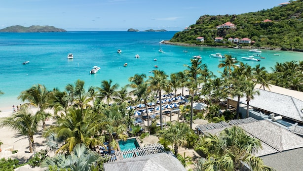 Een resort met een zwembad, strand en boten in het water.