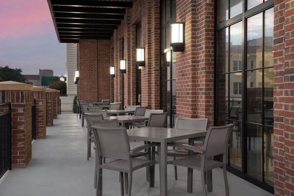 An outdoor patio area with brick walls, tables, and chairs.