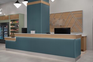 A reception desk with a modern design, a digital screen, and a counter with a card reader. - Holiday Inn Express Pensacola Downtown by IHG (Pensacola)