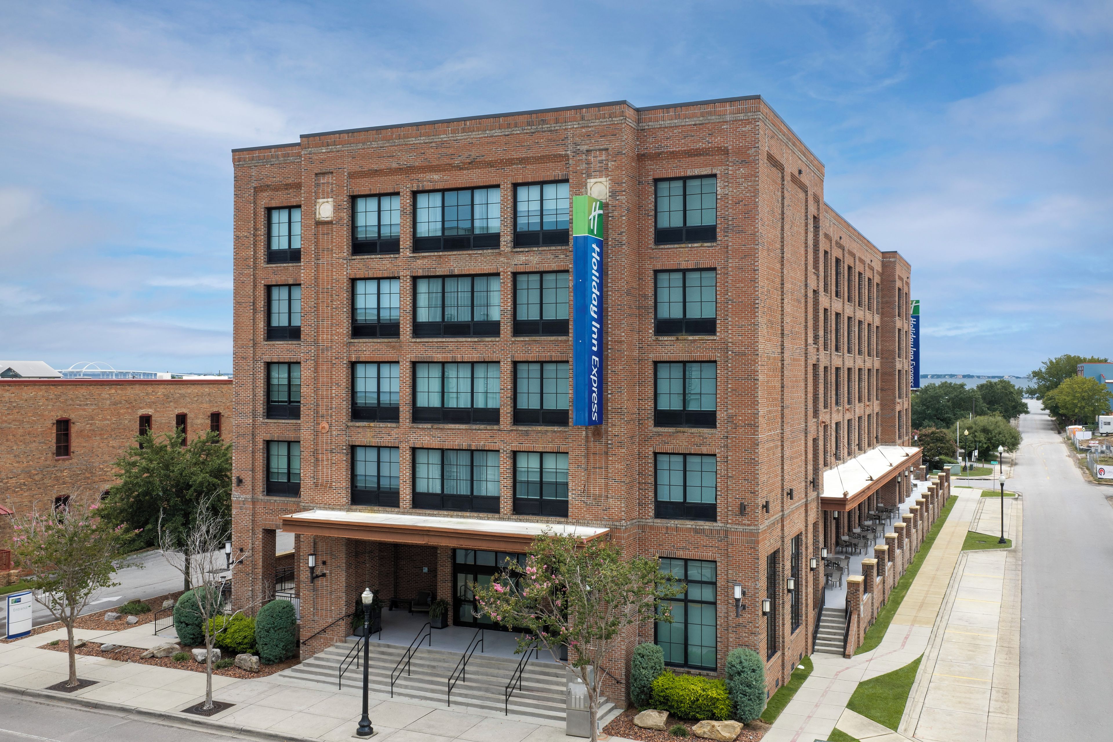 A multi-story hotel with a brick facade, large windows, and a blue sign indicating it is a Holiday Inn Express.