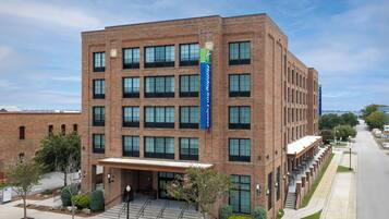 A multi-story hotel with a brick facade, large windows, and a blue sign indicating it is a Holiday Inn Express.