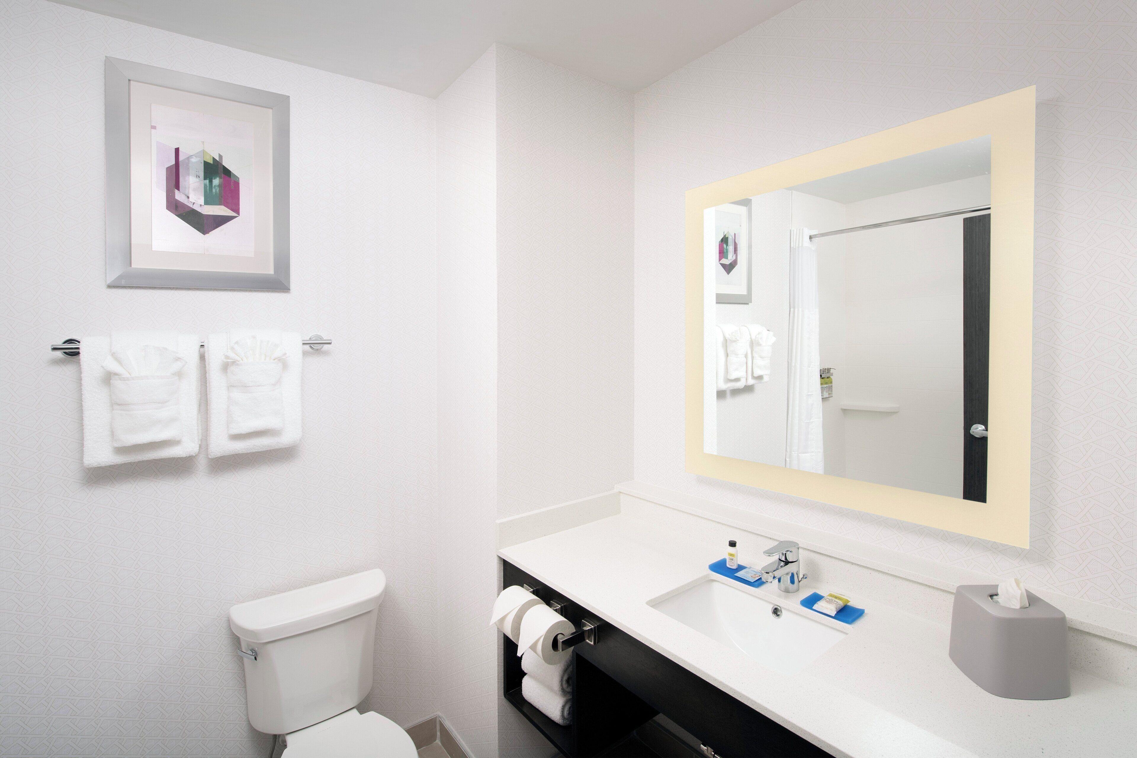A modern bathroom with a toilet, sink, and mirror. There are two towels hanging on the wall.