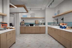 A modern kitchen with wooden cabinets, a microwave, and a breakfast bar. - Holiday Inn Express Pensacola Downtown by IHG (Pensacola)