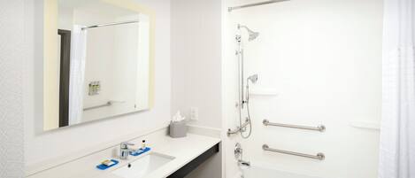 A bathroom with a white sink, mirror, and bathtub.