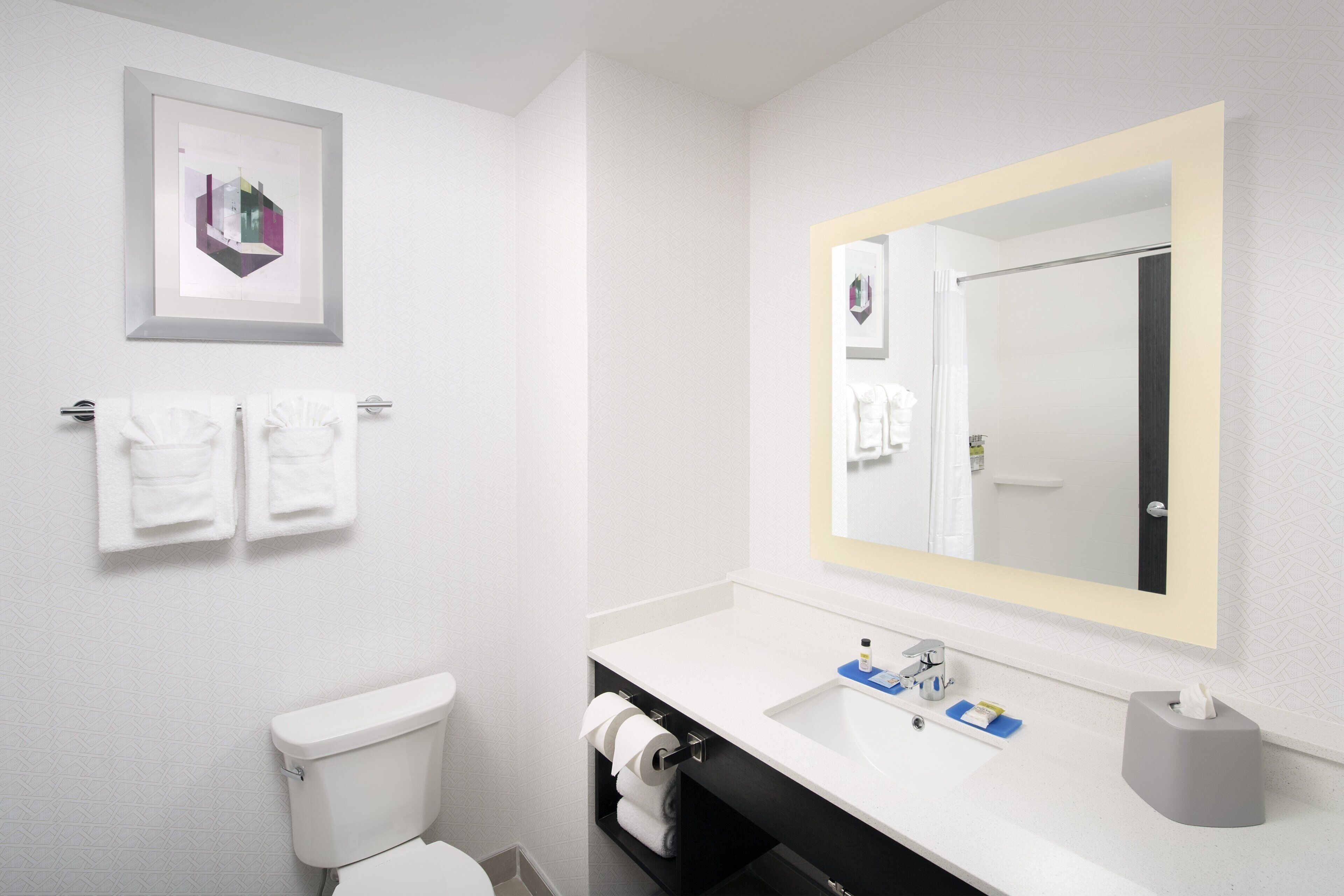 A modern bathroom with a toilet, sink, and a large mirror. There are two towels hanging on a towel rack.