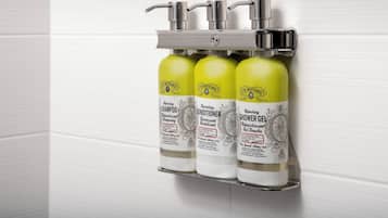 Ein wandmontierter Spender mit drei Flaschen J.R. Watkins Produkten: Shampoo, Conditioner und Duschgel.