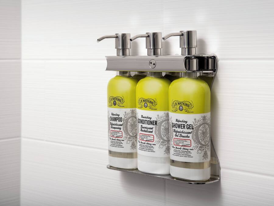 Ein wandmontierter Spender mit drei Flaschen J.R. Watkins Produkten: Shampoo, Conditioner und Duschgel.