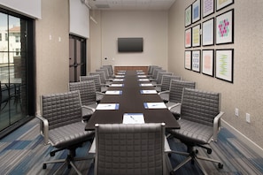A conference room with a long table, multiple chairs, a flat-screen TV, and framed artwork on the walls. - Holiday Inn Express Pensacola Downtown by IHG (Pensacola)