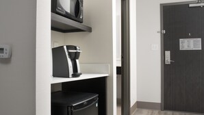 Quarto de hotel com micro-ondas numa prateleira, cafeteira e frigorífico.