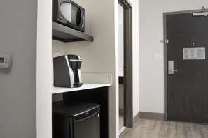 A hotel room with a microwave on a shelf, a coffee maker, and a refrigerator. - Holiday Inn Express Pensacola Downtown by IHG (Pensacola)