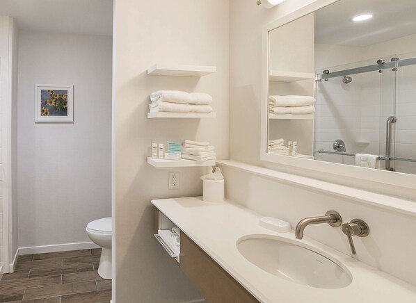 A modern bathroom with a white sink, a large mirror, and a glass shower enclosure.
