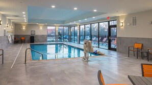 An indoor swimming pool with clear glass walls, a lifeguard chair, and a pool ladder.
