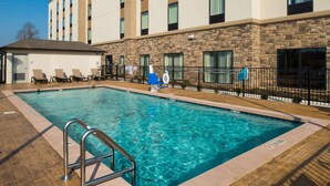 A hotel pool area with a clear pool, lounge chairs, and a stone facade. - Hampton Inn Paragould (Paragould)