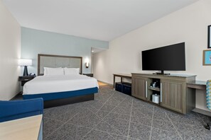 A hotel room with a bed, a desk, a television, and a bathroom.