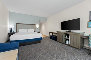 Habitación de hotel con cama, escritorio, televisor y baño.