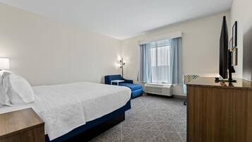 A hotel room with a bed, a desk, a chair, a television, and a window with curtains.