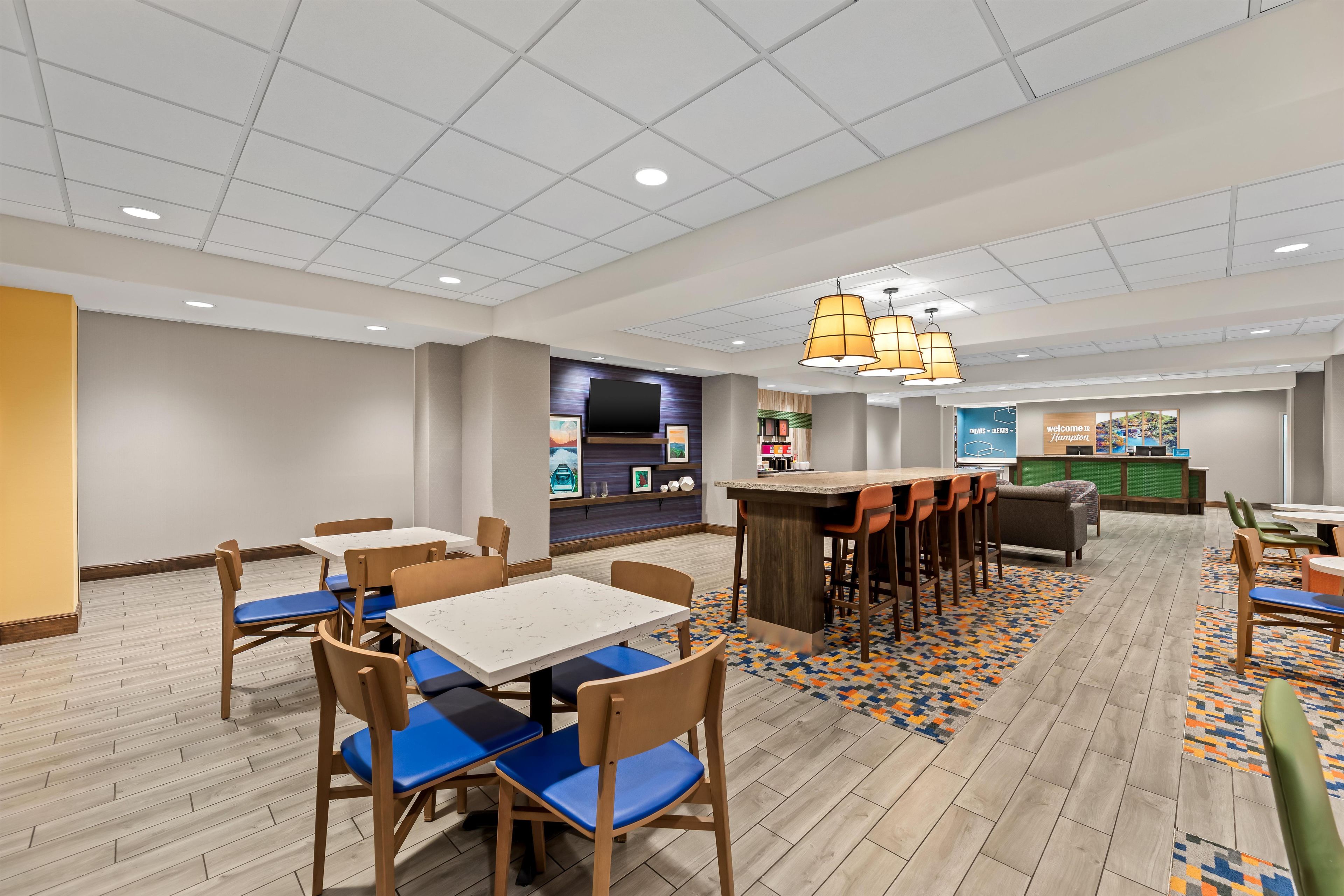 Un hall d’hôtel comprenant un bar, des espaces aménagés avec des sièges et un comptoir de réception.