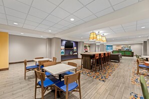 A hotel lobby with a bar area, seating arrangements, and a reception desk.