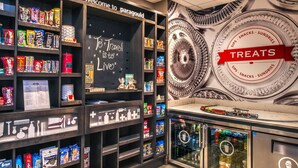 A traveler's lounge with shelves of snacks, a chalkboard with travel quotes, and a 'Treats' sign. - Hampton Inn Paragould (Paragould)