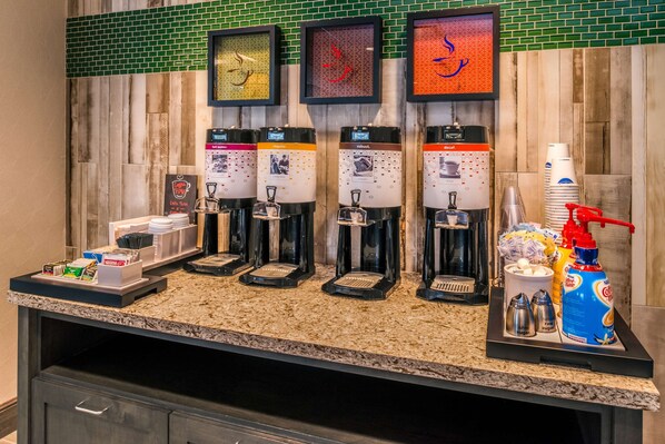 A coffee station with four dispensers, a menu board, and various coffee-related items.