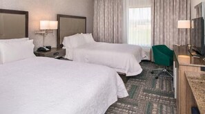 A hotel room with two beds, a desk, a chair, and a television.