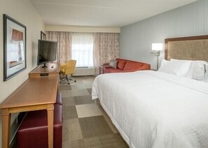 A hotel room with a bed, a desk with a chair, a television, and a window with curtains. - Hampton Inn Paragould (Paragould)