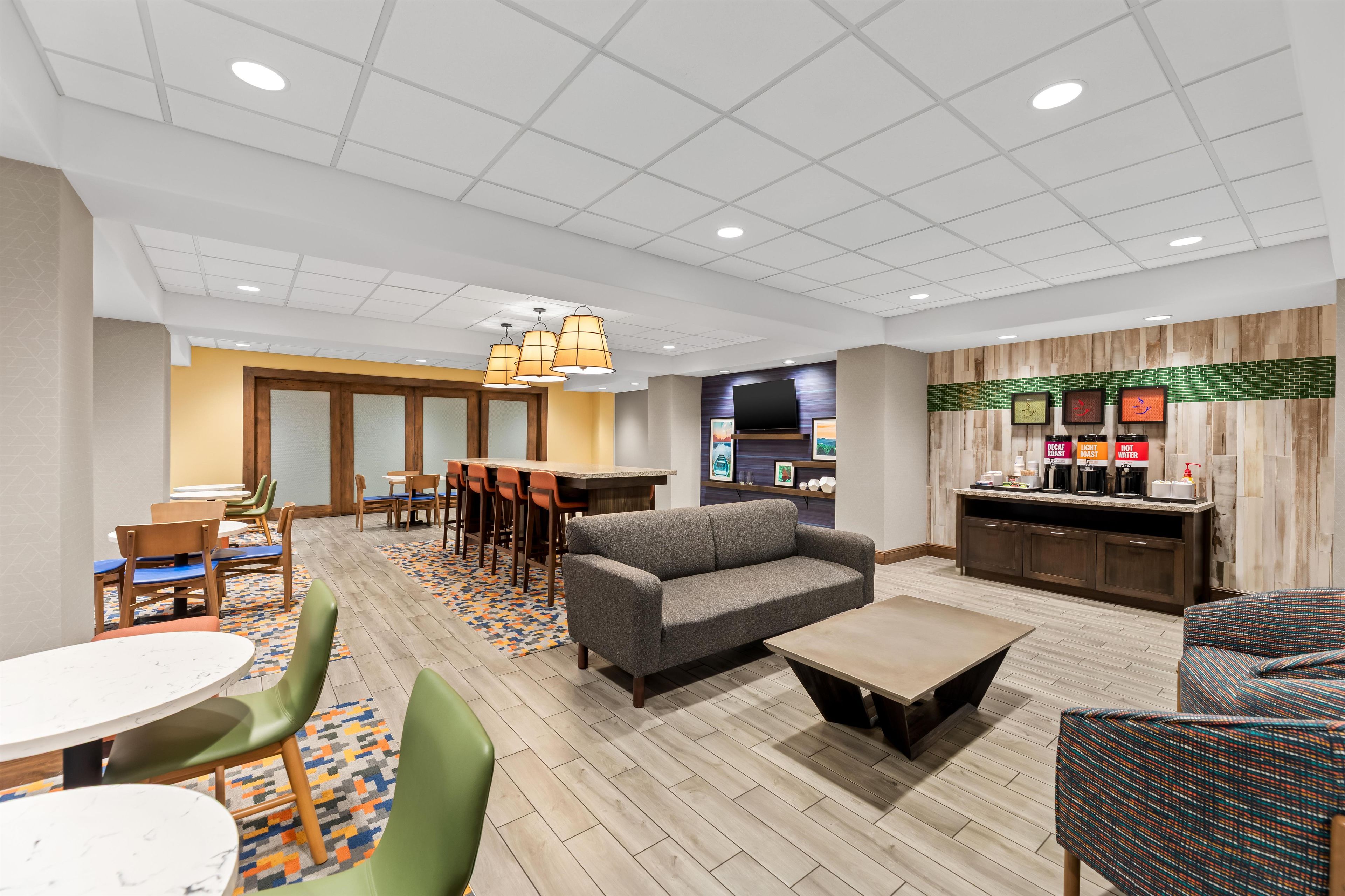 A hotel lobby with a seating area, a bar, and a television.