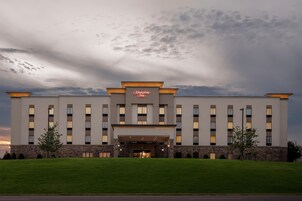 Un edificio de hotel grande y moderno con un letrero visible que dice 'Hampton Inn'.