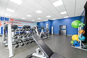 A gym with various exercise equipment, including dumbbells, a bench, and exercise balls.