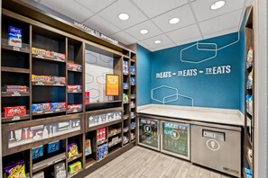 A snack and beverage section with shelves stocked with various brands and a wall with the text 'TREATS - TREATS - TREATS'. - Hampton Inn Paragould (Paragould)