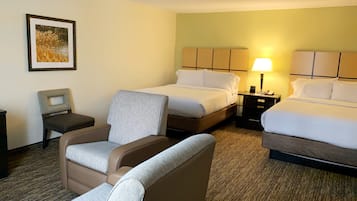 Een hotelkamer met twee bedden, een stoel, een nachtkastje en een lamp.