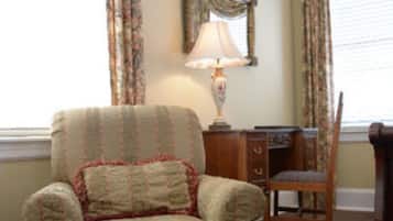 A room with a patterned armchair, a wooden desk, and a lamp.
