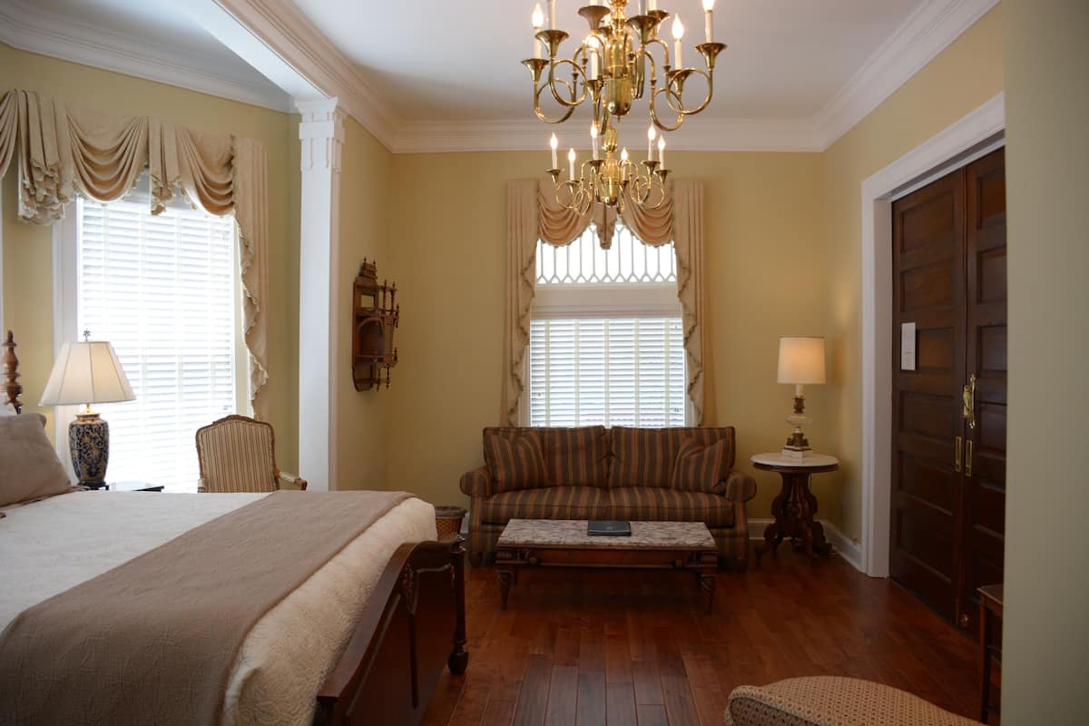 A hotel room with a large bed, a sofa, a coffee table, and a chandelier.