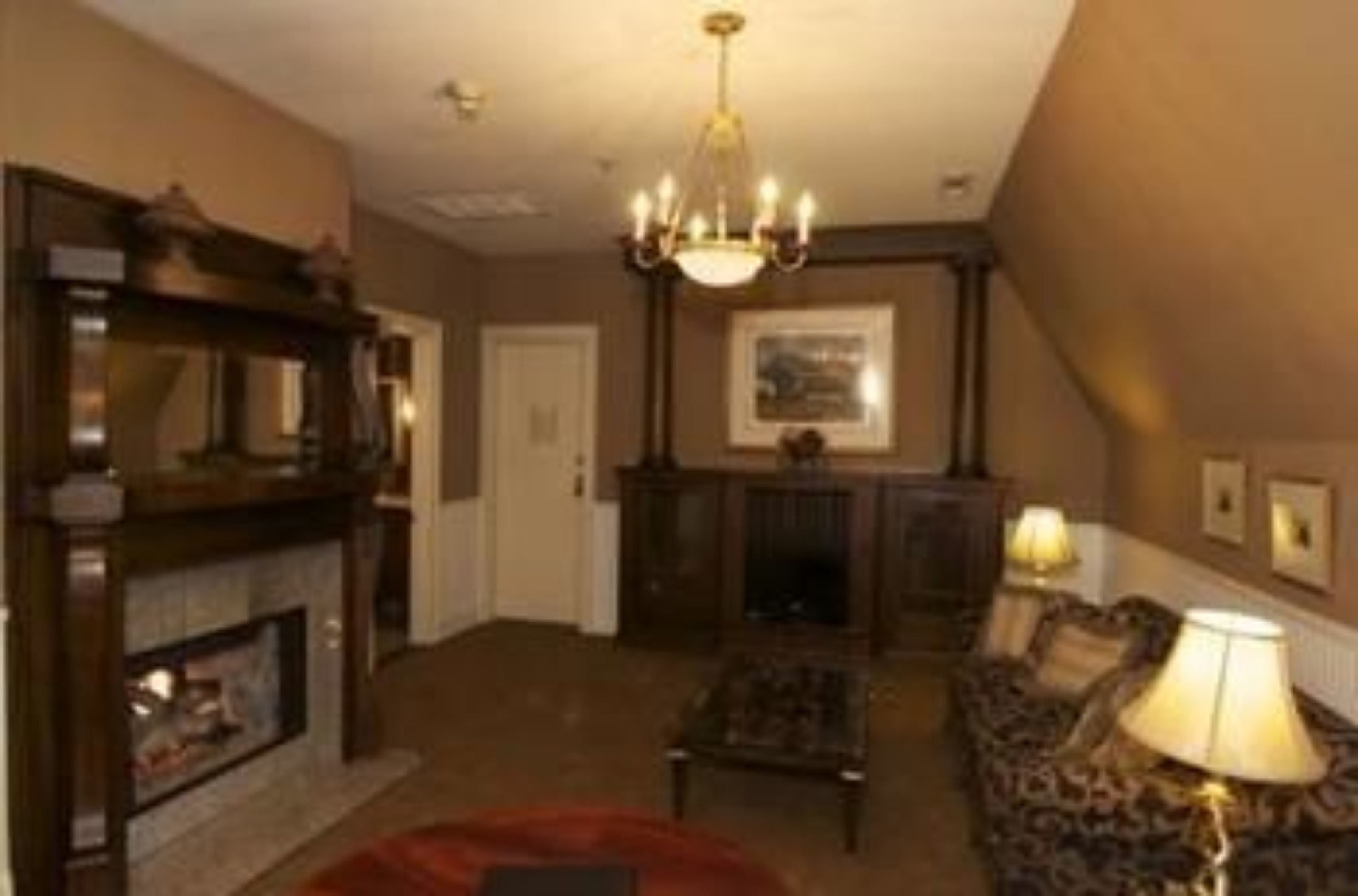 A traditional living room with a fireplace, a chandelier, and a patterned sofa.