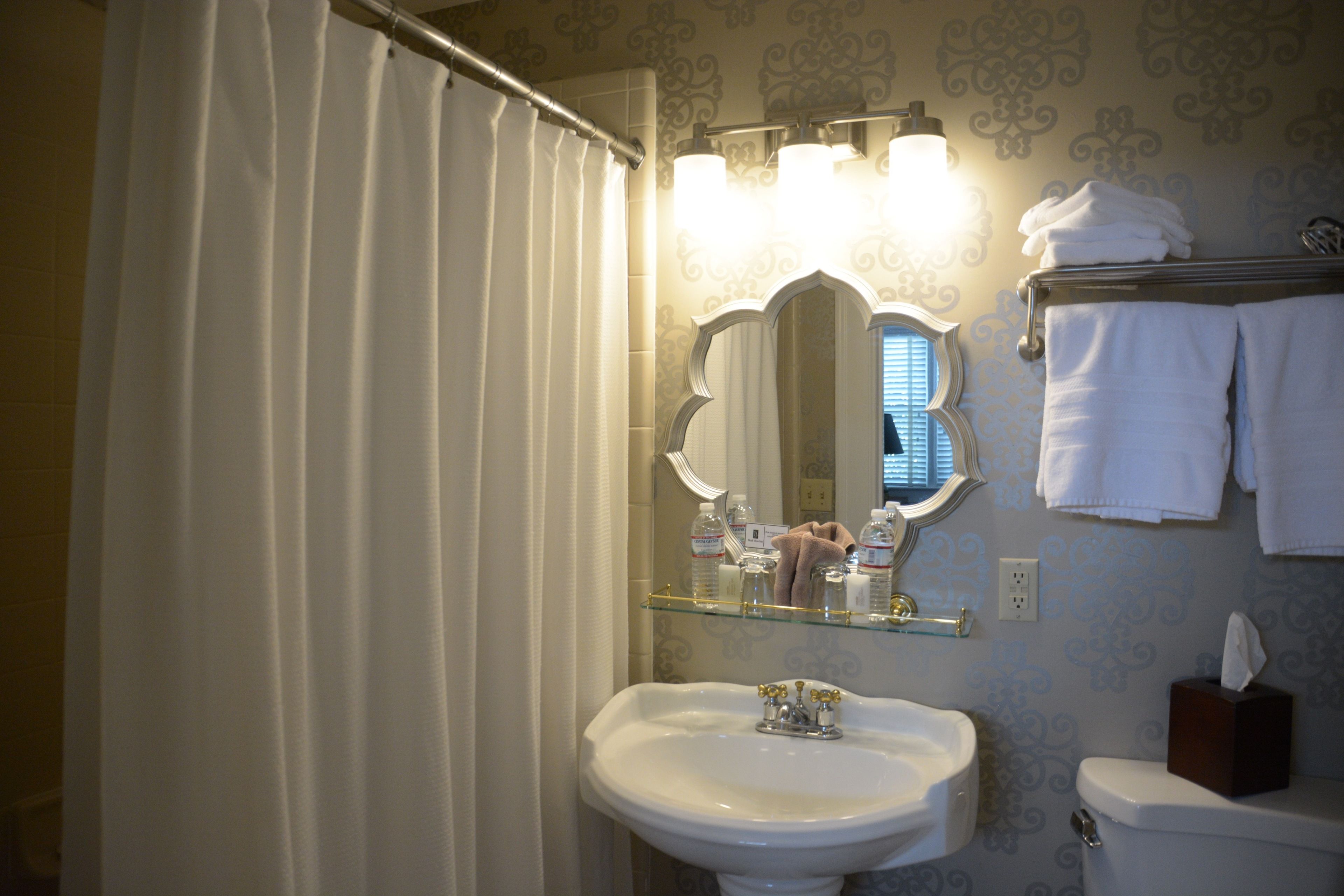 A bathroom with a white sink, a mirror, and a towel rack.
