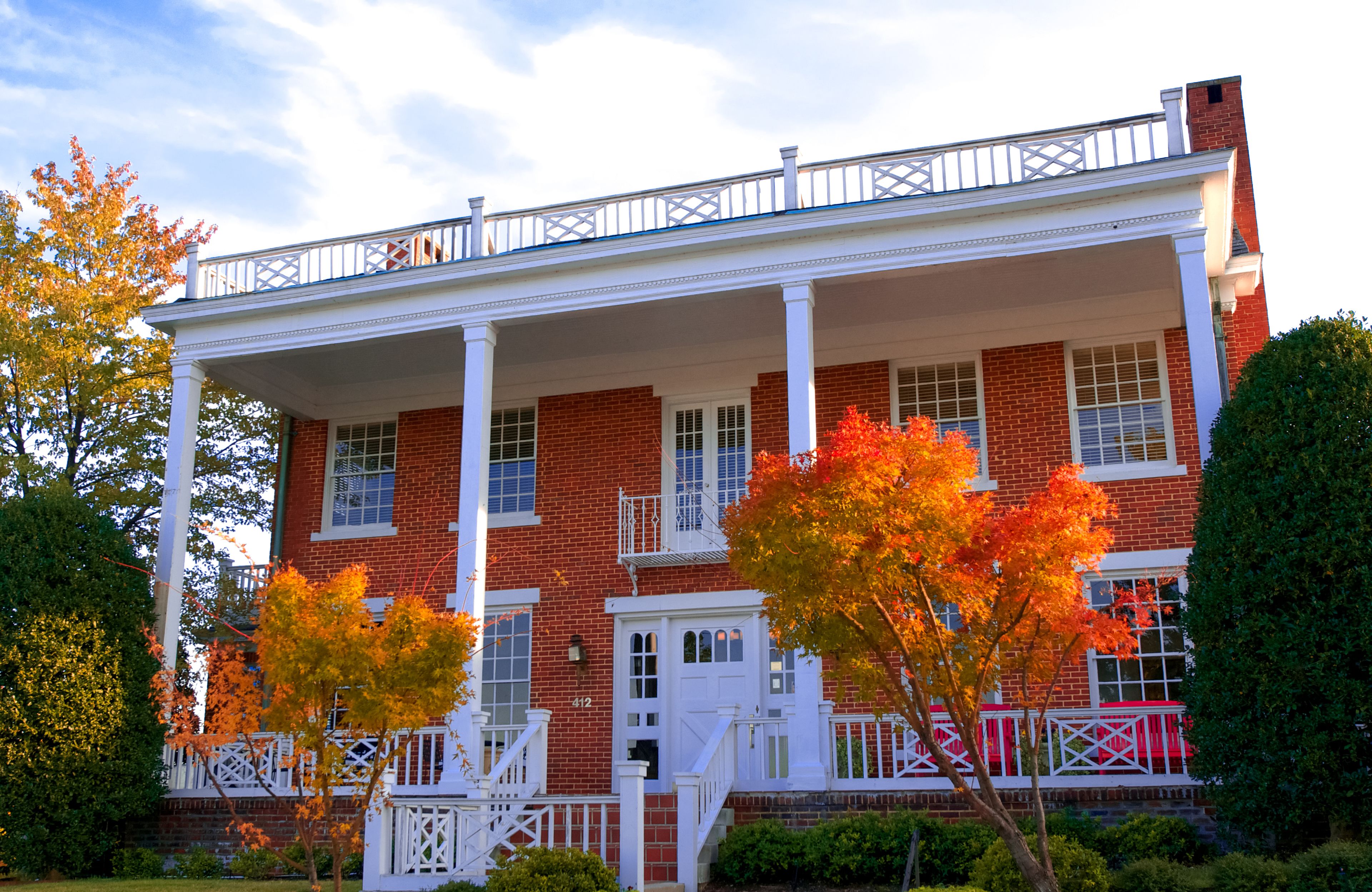 A two-story brick house with a white porch and a balcony.