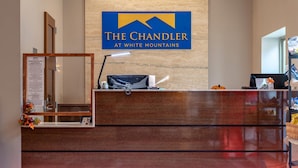 A reception desk with a sign reading "The Chandler at White Mountains," a mirror, a desk lamp, and a small pumpkin decoration.