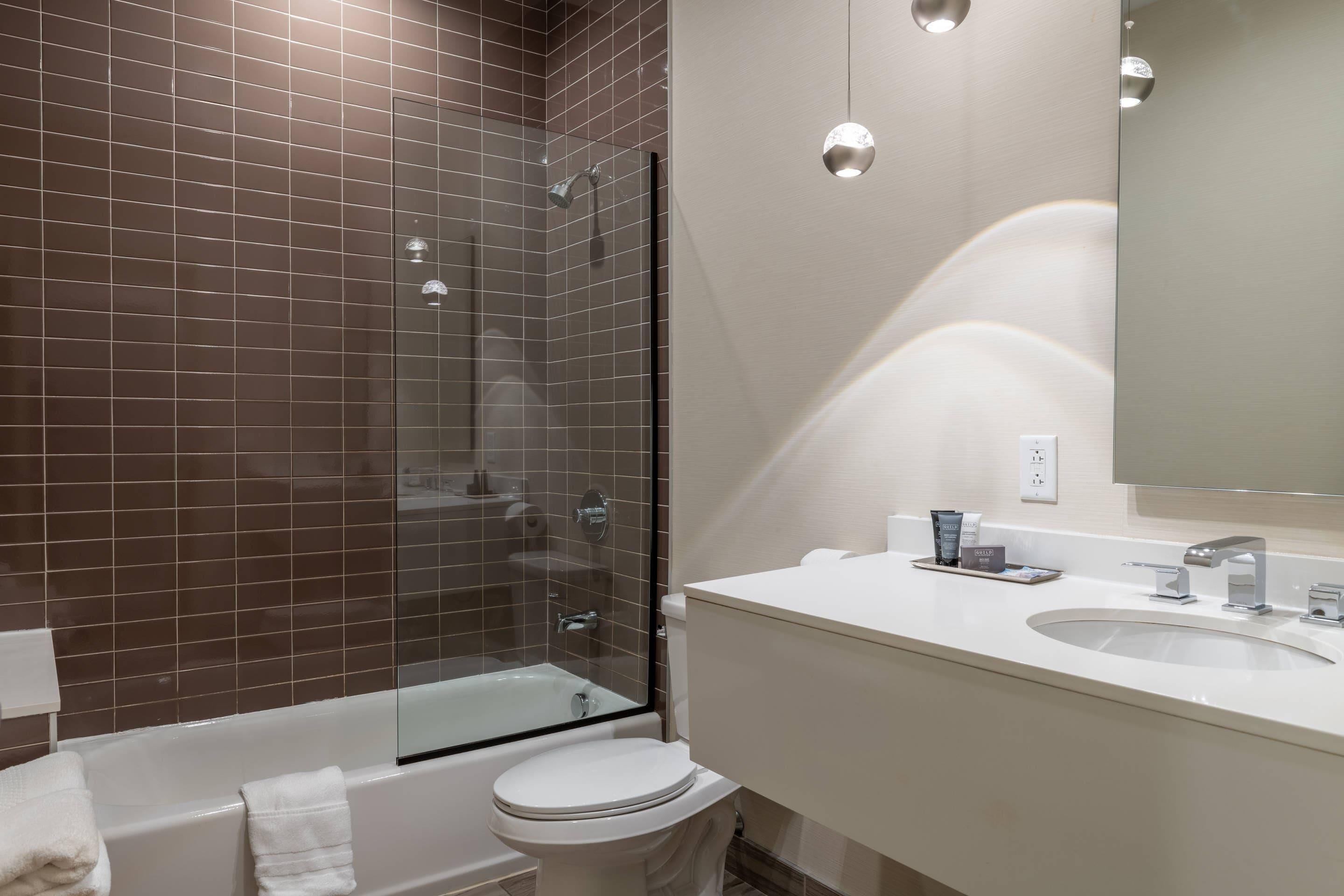 Un bagno con doccia vetrata, un water bianco e un lavabo con specchio.