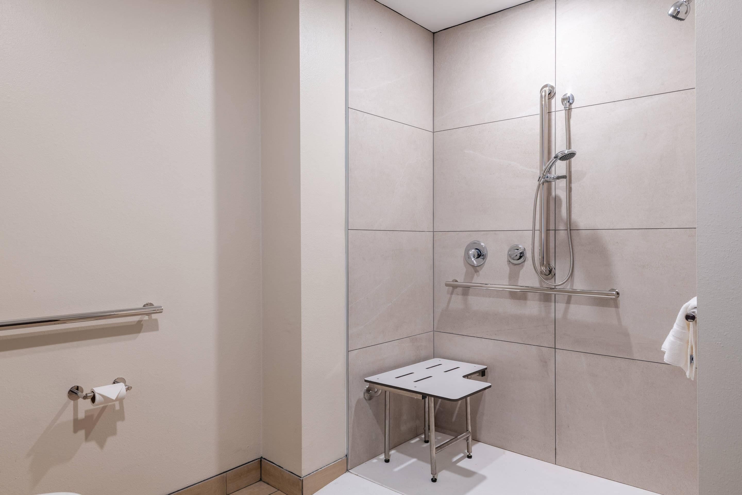 Een moderne badkamer met een douche, toilet en een klein tafeltje.